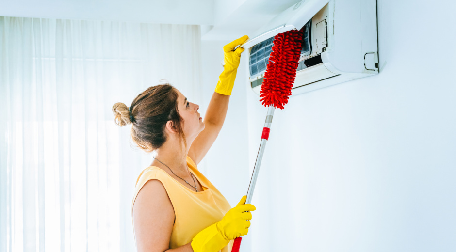 Woman dusts air conditioner filter