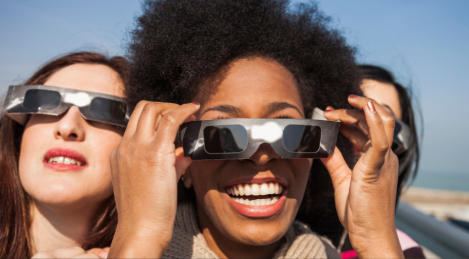 three women with eclipse glasses
